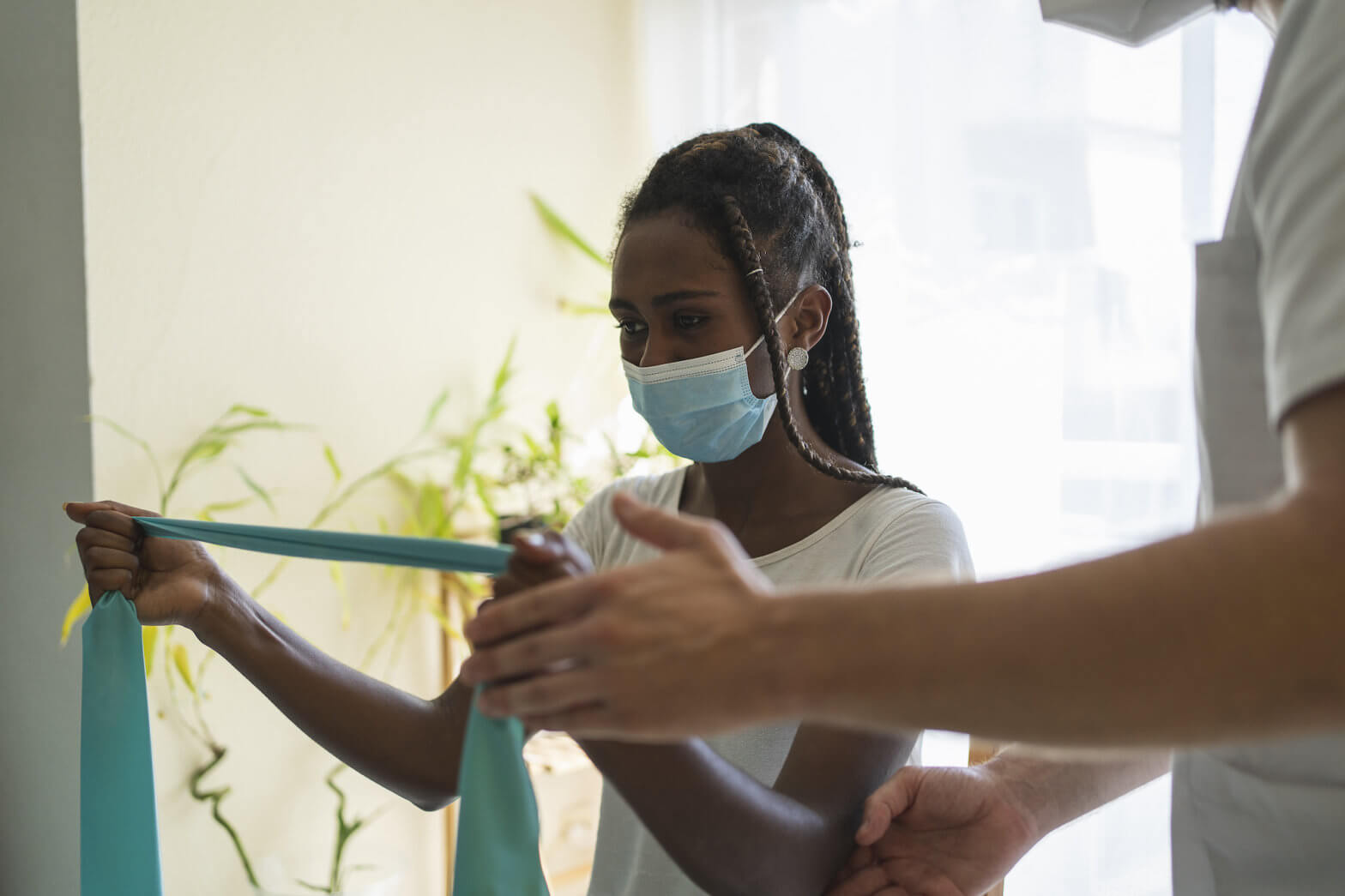 A woman uses a resistance band as a therapist supervises her